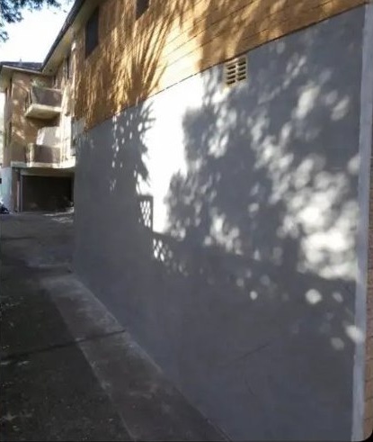 After: brick apartment side wall rendered in a smooth grey finish