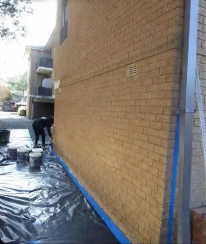 Before: brick apartment side wall rendered in a smooth grey finish